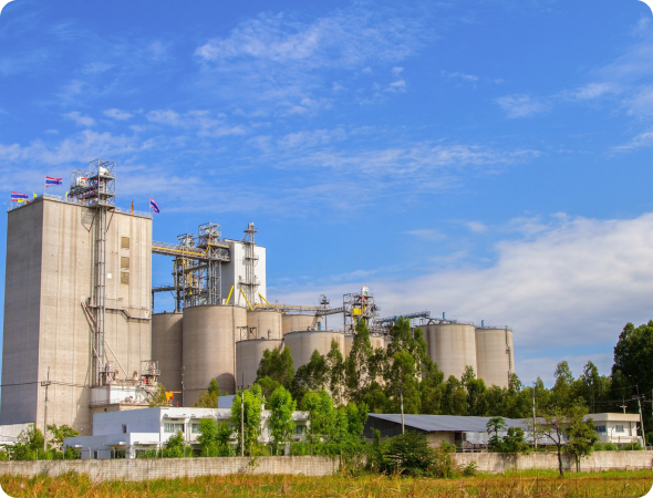 Cement grinding plant with tall processing tower, cylindrical silo, and large pipeline system.